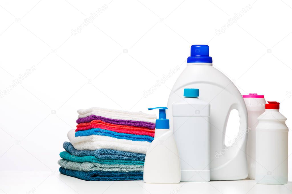 Photo of bottles of cleaning products and multi-colored cloths on clean white background