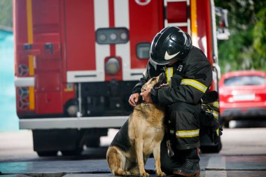 Photo of fireman squatting next to service dog near fire engine clipart