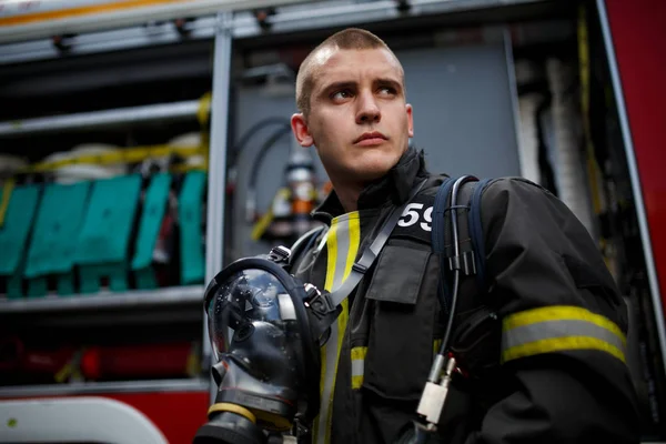 Foto do jovem bombeiro perto do carro de bombeiros — Fotografia de Stock