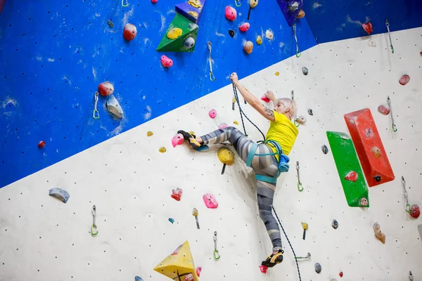 Foto von hinten: junge Sportlerin im gelben T-Shirt klettert beim Training an Wand — Stockfoto