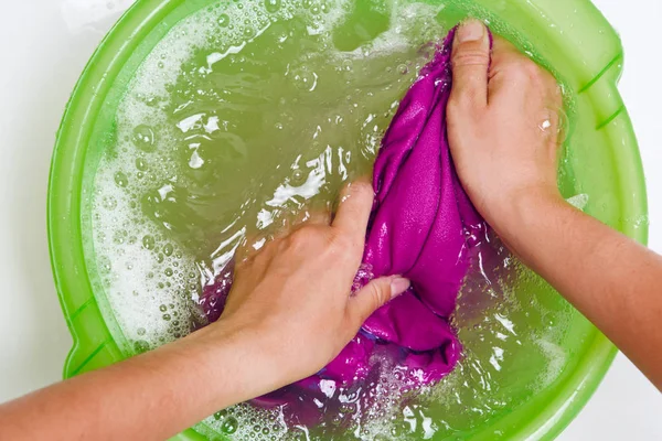 Foto sopra le mani della donna che lavano i vestiti viola nel bacino verde — Foto Stock