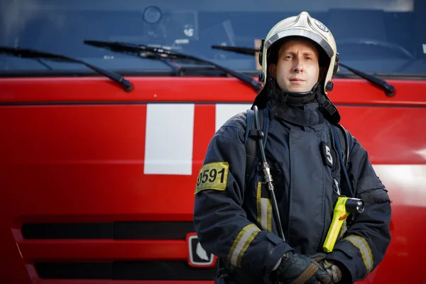 Photo of young fireman in front of red car — Stock Photo, Image