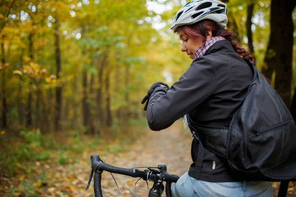 Foto de morena sorridente no capacete sentado na bicicleta no outono — Fotografia de Stock