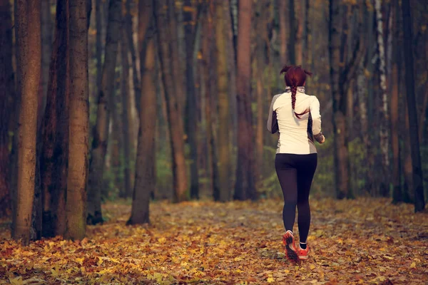 Foto de la espalda de una joven deportista corriendo en el bosque — Foto de Stock
