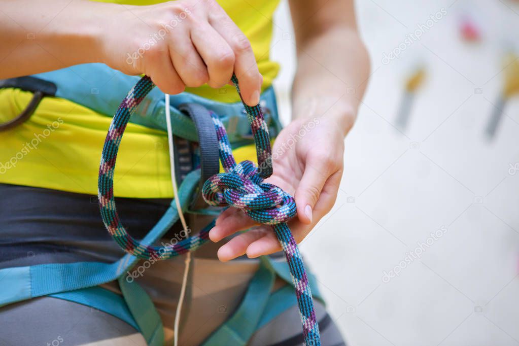 Close-up photo of athlete woman climber tying knot at gym