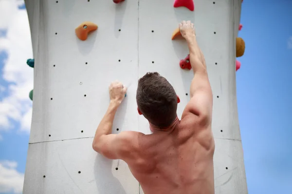 Foto da parte de trás do homem desportivo subindo em pedra — Fotografia de Stock