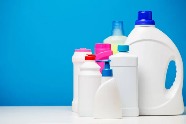 Foto bottiglie di prodotti per la pulizia isolati su sfondo blu , — Foto Stock