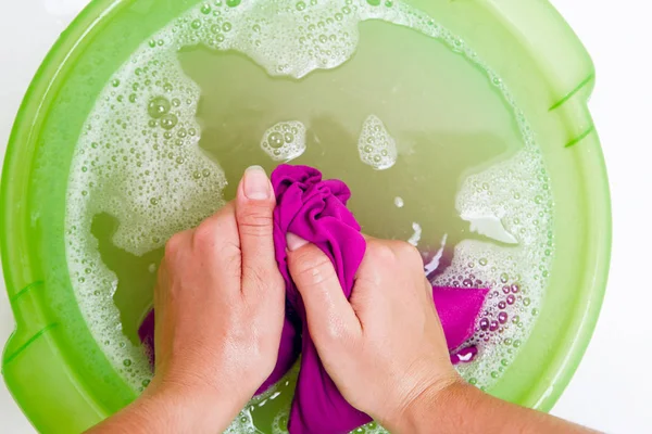 Photo on top of female hands washing violet clothes in green basin with foam water — Stock Photo, Image