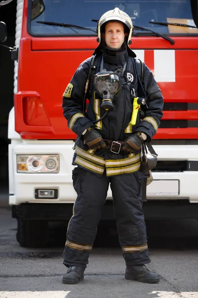 Photo in full growth of fireman on background of fire engine machine at station — Stock Photo, Image