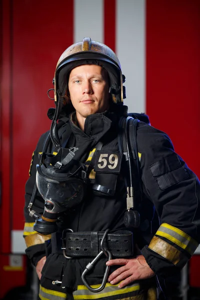 Φωτογραφία: σοβαρή πυροσβέστης φορώντας κράνος με μάσκα αερίων στο φόντο του πυροσβεστικό όχημα — Φωτογραφία Αρχείου