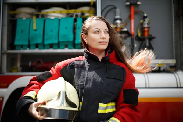 Foto einer jungen Frau mit langen Haaren, die neben einem Feuerwehrauto zur Seite schaut — Stockfoto