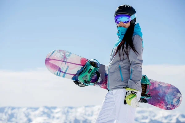 Foto van vrouw met snowboard helm wandelen op sneeuw bergen achtergrond — Stockfoto