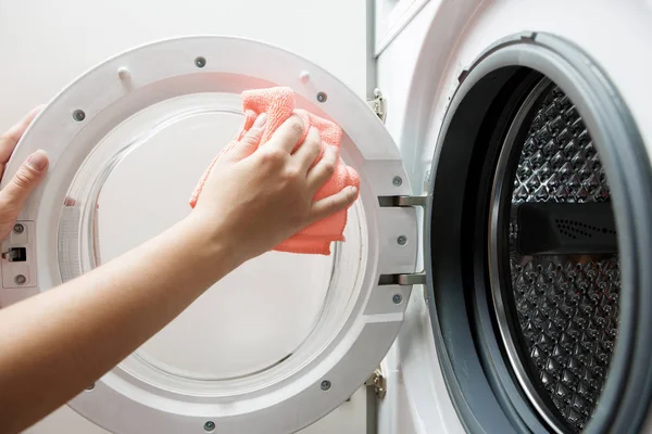 Photo of woman hands wiping orange cloth washing machine — Stock Photo, Image