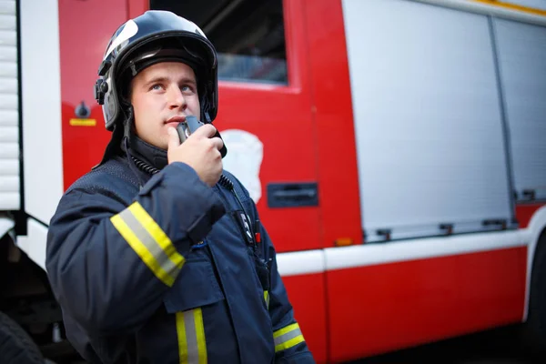 Foto do bombeiro falando sobre walkie-talkie com motor de incêndio — Fotografia de Stock