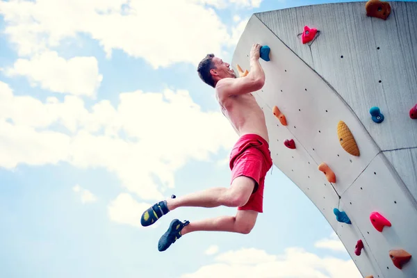 Фото спортивного человека, балансирующего на стене для восхождения на облачное небо — стоковое фото