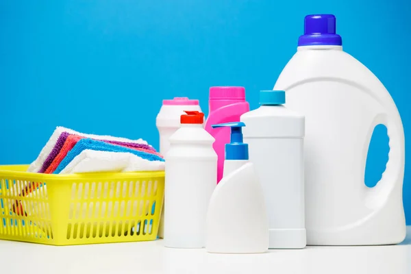 Botellas de fotos de productos de limpieza y toallas multicolores en cesta aislada sobre fondo azul — Foto de Stock