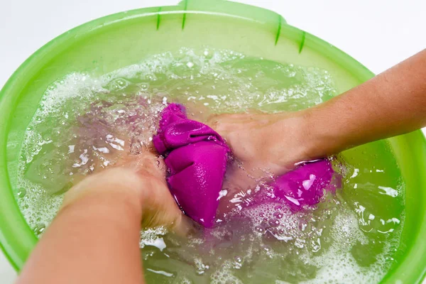 Foto en la parte superior de las manos de la niña lavando la ropa violeta en el lavabo verde — Foto de Stock