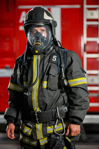 Foto de bombero en máscara de gas y casco cerca del camión de bomberos — Foto de Stock