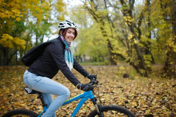 Obraz szczęśliwy dziewczyna w hełm jazdy na rowerze w jesieni — Zdjęcie stockowe