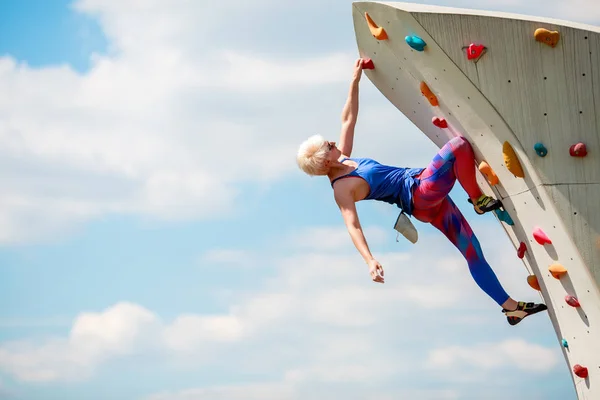Foto von der Seite der Sportlerin, die an einem felsigen Sommertag klettert — Stockfoto