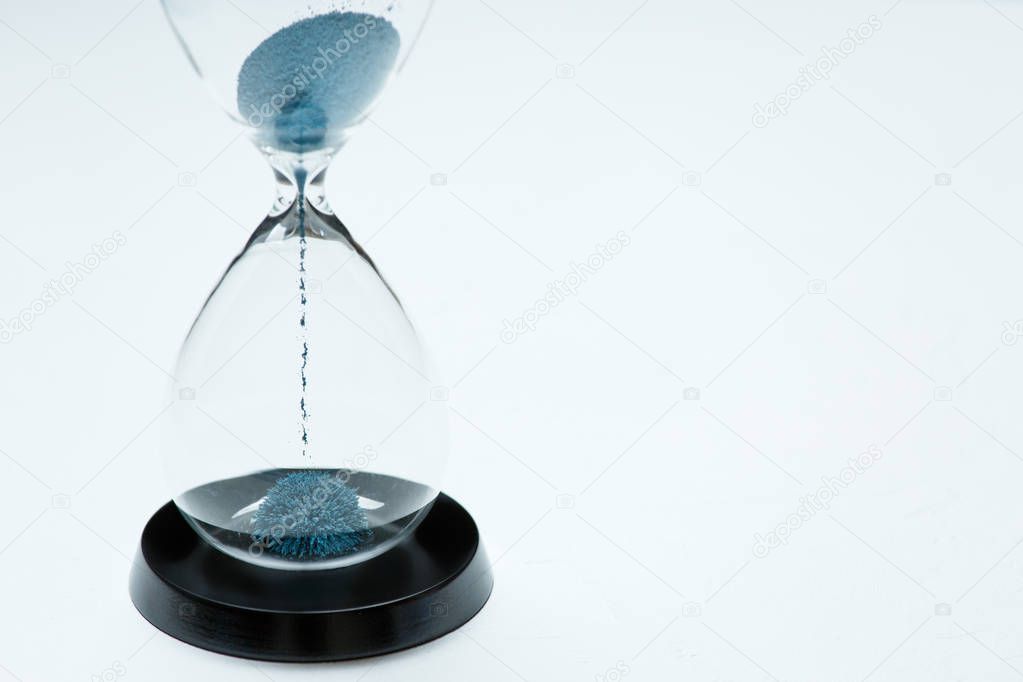 Photo of hourglass with blue sand on isolated white background,