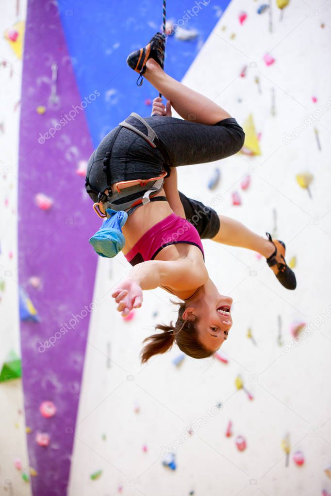 Photo of young athlete hanging upside down on wall for rock climbing