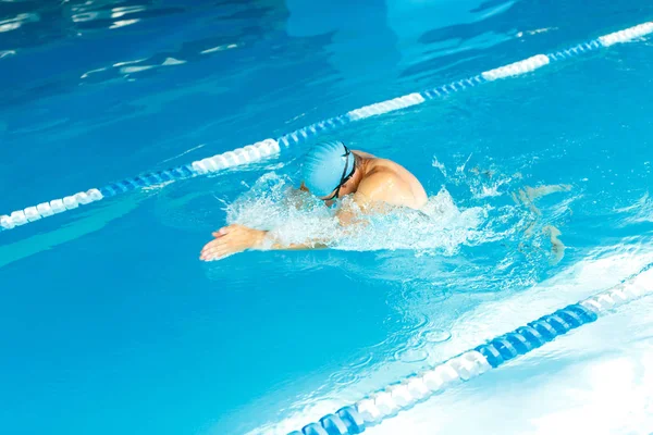 Photo of athlete man in blue rubber cap floating under water in pool — Stock Photo, Image