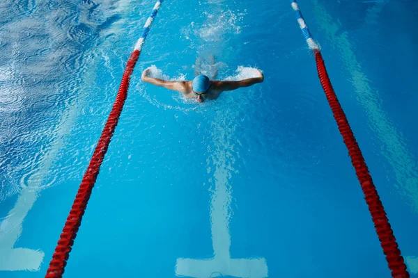 Foto van sport man in blauwe dop zwemmen in zwembad — Stockfoto