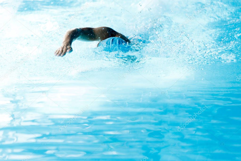 Photo of man swimming in style of crawl in swimming pool on