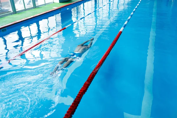Foto op de top van sport man in blauwe cap op pad in zwembad onder water zwemmen — Stockfoto