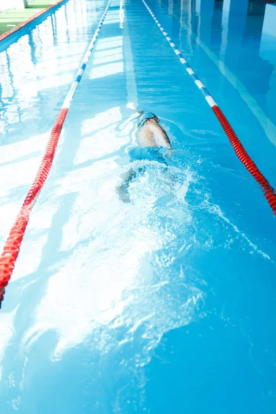 Sportos fiatalember a kék sapka, úszás a medencében vissza-fotó — Stock Fotó