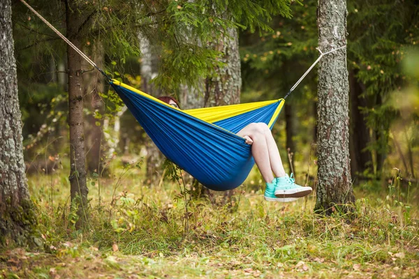 Bilden av brunett vilar i hängmatta i skogen — Stockfoto