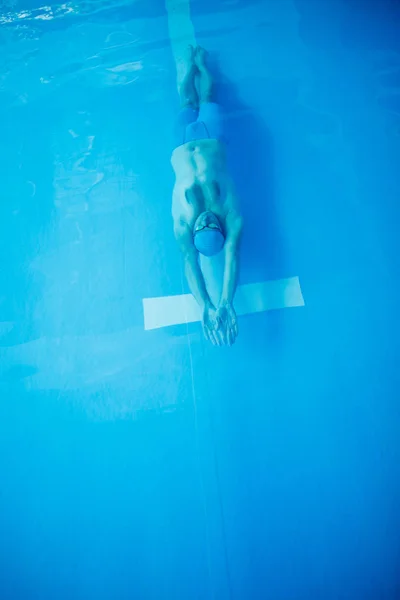 Foto no topo do jovem desportista nadando na parte de trás da piscina interior — Fotografia de Stock