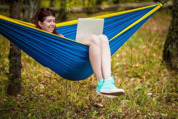 Foto de morena descansando na rede com laptop na floresta — Fotografia de Stock