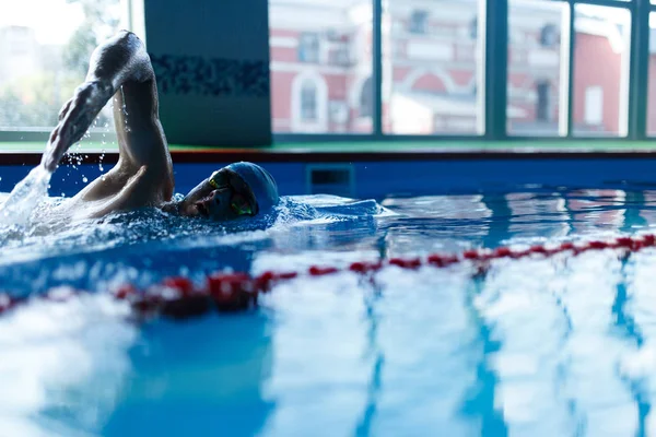 Photo of man swimming in pool indoors