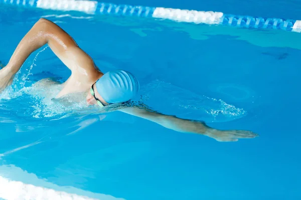 Bild des Athleten Mann mit blauer Mütze schwimmt auf Pfad in Pool — Stockfoto