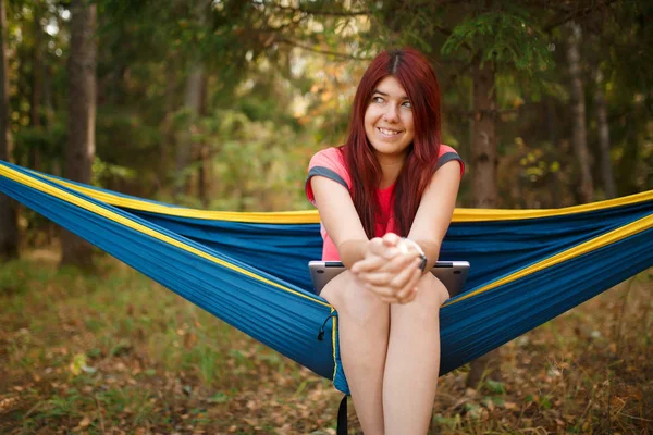 Photo of woman looking in camera with laptop sitting in hammock — Stock Photo, Image