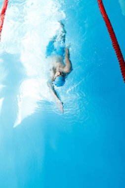 Fotoğraf arka yüzme havuzunda yüzme mavi şapkalı sportif delikanlı üstüne