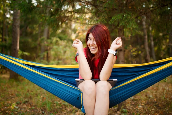 Foto della ragazza che guarda in macchina fotografica con il computer portatile seduto in amaca — Foto Stock