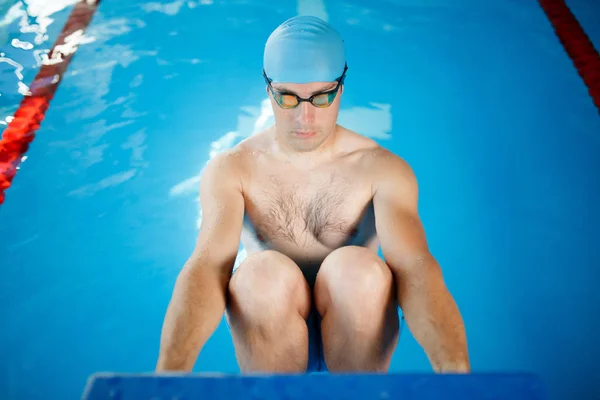 Photo athlete in blue rubber cap and glasses pushing in pool