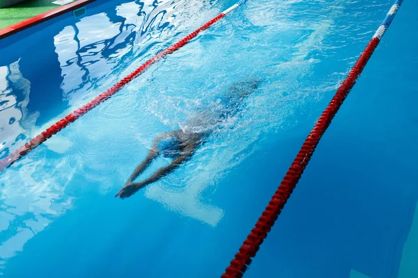 Imagen del deportista con gorra azul nadando en la piscina durante el entrenamiento — Foto de Stock