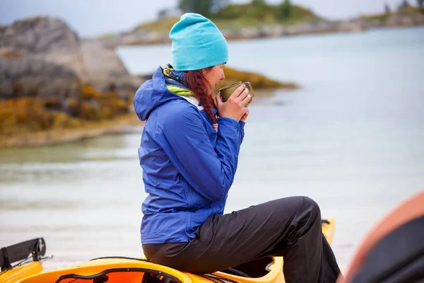 Vista laterale del turista femminile che beve dalla tazza seduta sul kayak sul fiume — Foto Stock
