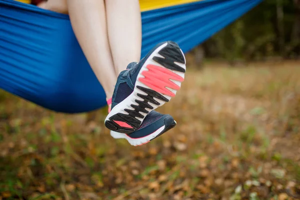 Bild av kvinna med hängande ben i sneakers ligga i hängmatta i skogen — Stockfoto