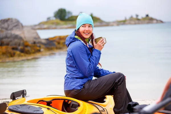 Foto av glad kvinnlig turist med kopp sitter på kajak på floden, — Stockfoto