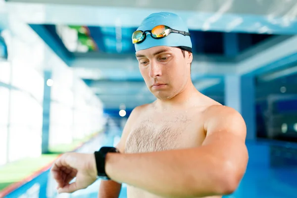 Photo of young swimmer with timer on arm standing in pool