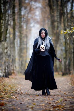 Cadı kız kafatası ile siyah pelerin içinde tam büyüme görüntüsünü