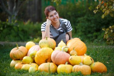Fotoğraf mutlu bahçıvan esmer yeşil çim üzerinde kabak hasat arasında gri önlük