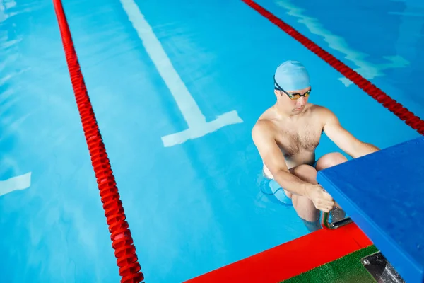 Afbeelding van de sportieve zwemmer mens in blauwe dop aan zijkant in zwembad — Stockfoto