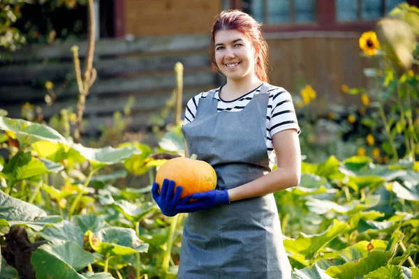Imagem de mulher sorridente com abóbora nas mãos no jardim — Fotografia de Stock