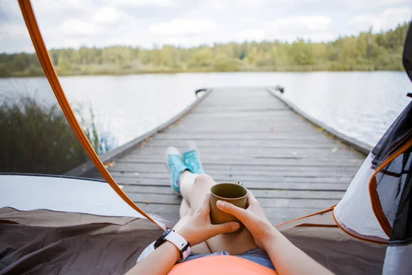 Bild av kvinna med järn Mugg i händer sitter på träbro vid floden — Stockfoto